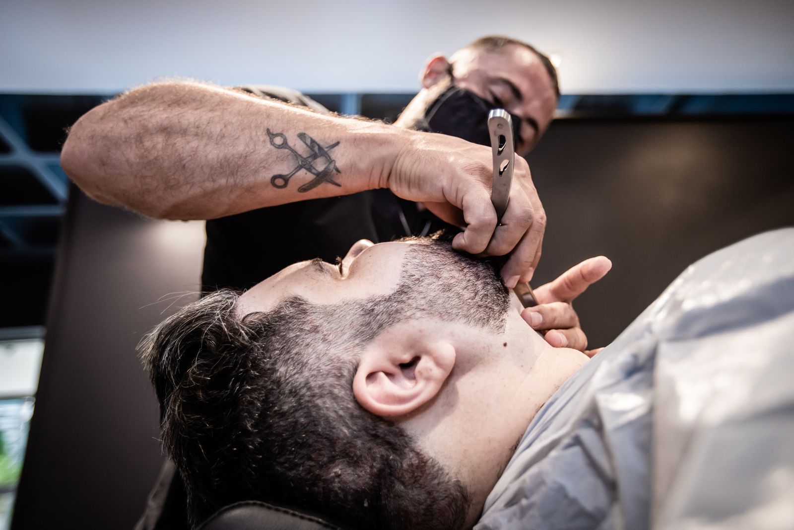 Professional barber carefully trimming a client's beard